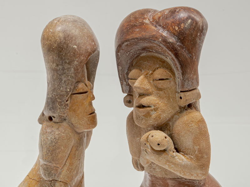 Two pottery figures facing each other. One is ancient and one is contemporary.