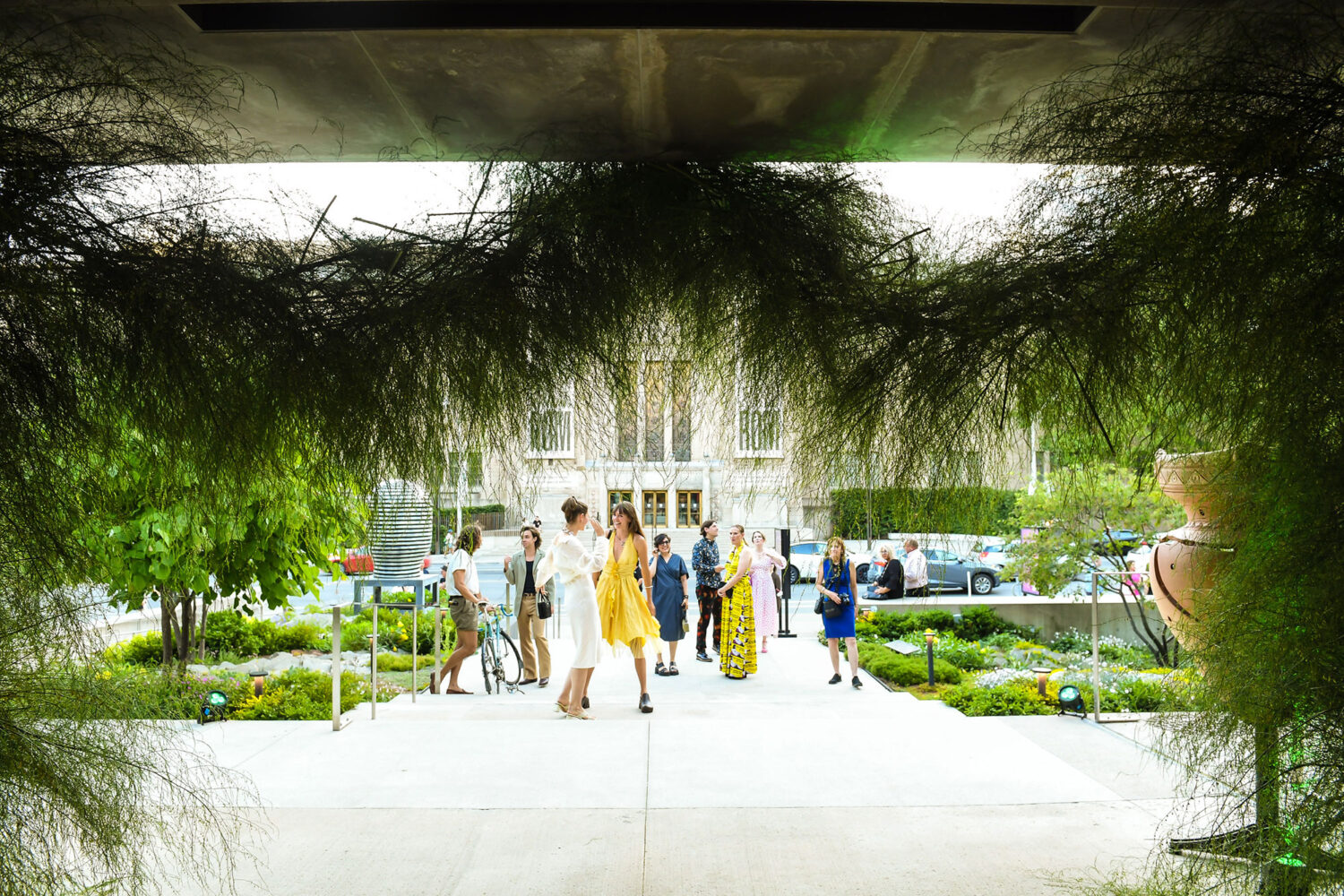 Guests is formal attire walking up the steps of the Gardiner which is draped with green plants