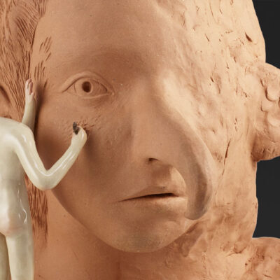 Headless figure sculpting a large clay bust