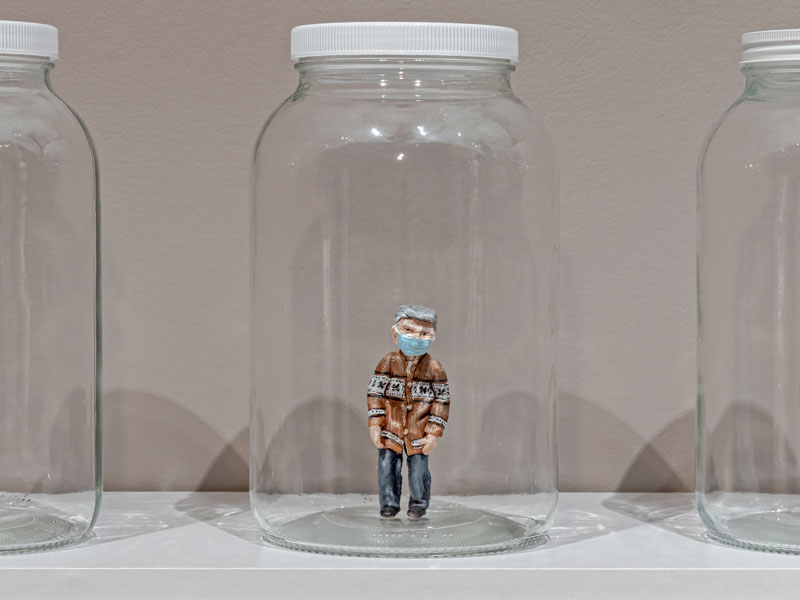 A glass mason jar containing a miniature polymer clay figure of an elderly man