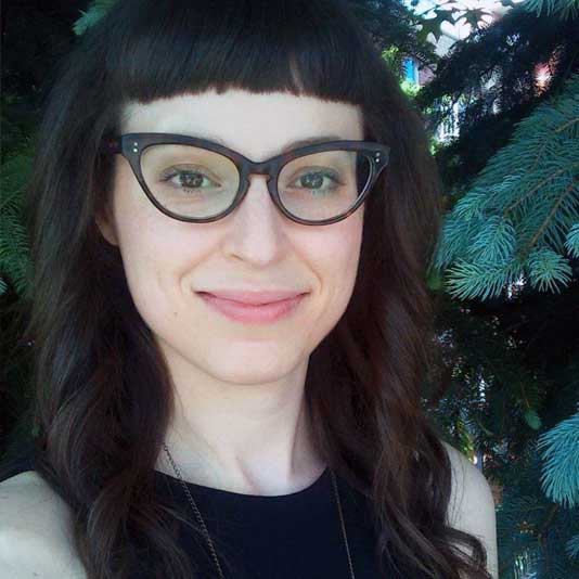 A white woman with cat-eye glasses smiling at the camera