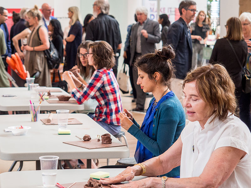 A room of people working with clay at tables in the exhibition hall