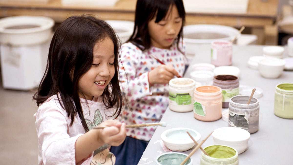 Two girls mixing clay glaze