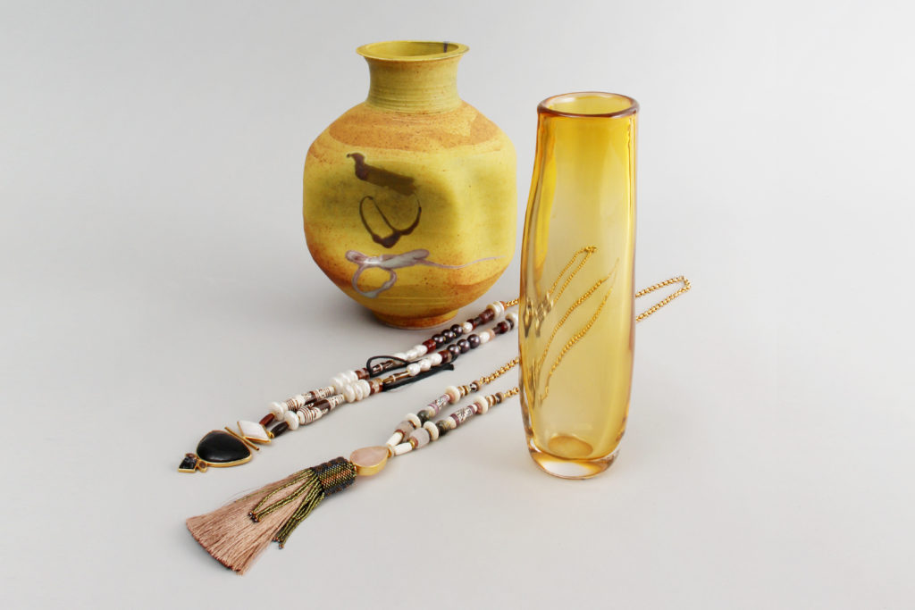 A yellow glass vase, a round yellow ceramic vase, and two yellow-toned necklaces